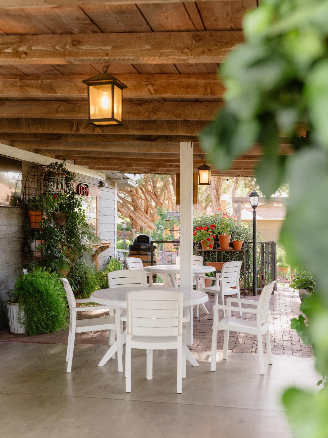 Covered patio with cafe tables and lanterns for an intimate outdoor reception
